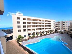 A hotel with a swimming pool, multiple balconies, and a view of the sea. - Rentenerife Casa Lola Medano Beach (Medano, El)