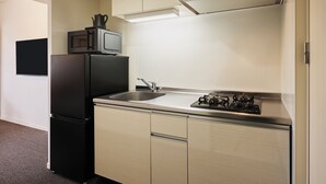 A compact kitchenette with a refrigerator, microwave, sink, and gas stove. - Residence Hotel Hakata Sumiyoshi (Fukuoka)