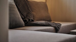 A sofa with a blanket and pillows. - Residence Hotel Hakata Sumiyoshi (Fukuoka)