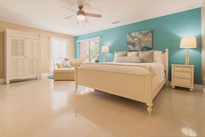 A bedroom with a bed, nightstands, a chair, a ceiling fan, and a window. - Eagle Beach - 3bed - 3 Bath - Ocean View - Oceania (Oranjestad)