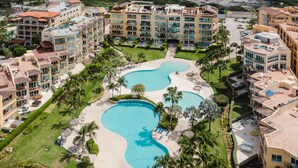 A resort with multiple swimming pools, palm trees, and a well-maintained lawn. - Eagle Beach - 3bed - 3 Bath - Ocean View - Oceania (Oranjestad)
