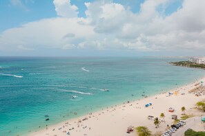 A beach with clear turquoise waters, a sandy shore, and a row of parked cars. - Eagle Beach - 3bed - 3 Bath - Ocean View - Oceania (Oranjestad)