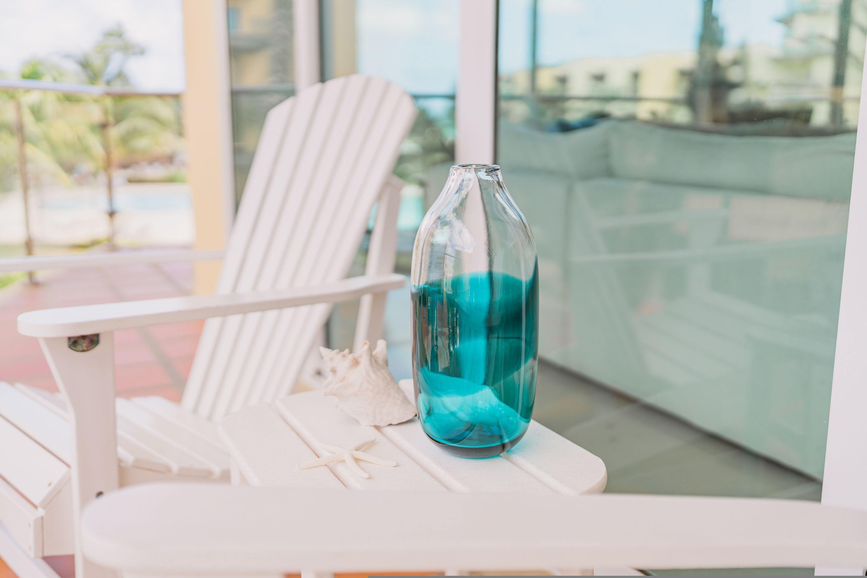 Una silla blanca con una botella de vidrio que contiene un líquido azul sobre una mesa.