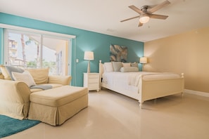 A bedroom with a bed, a sofa, a nightstand, a ceiling fan, and a view of the outside. - Eagle Beach - 3bed - 3 Bath - Ocean View - Oceania (Oranjestad)