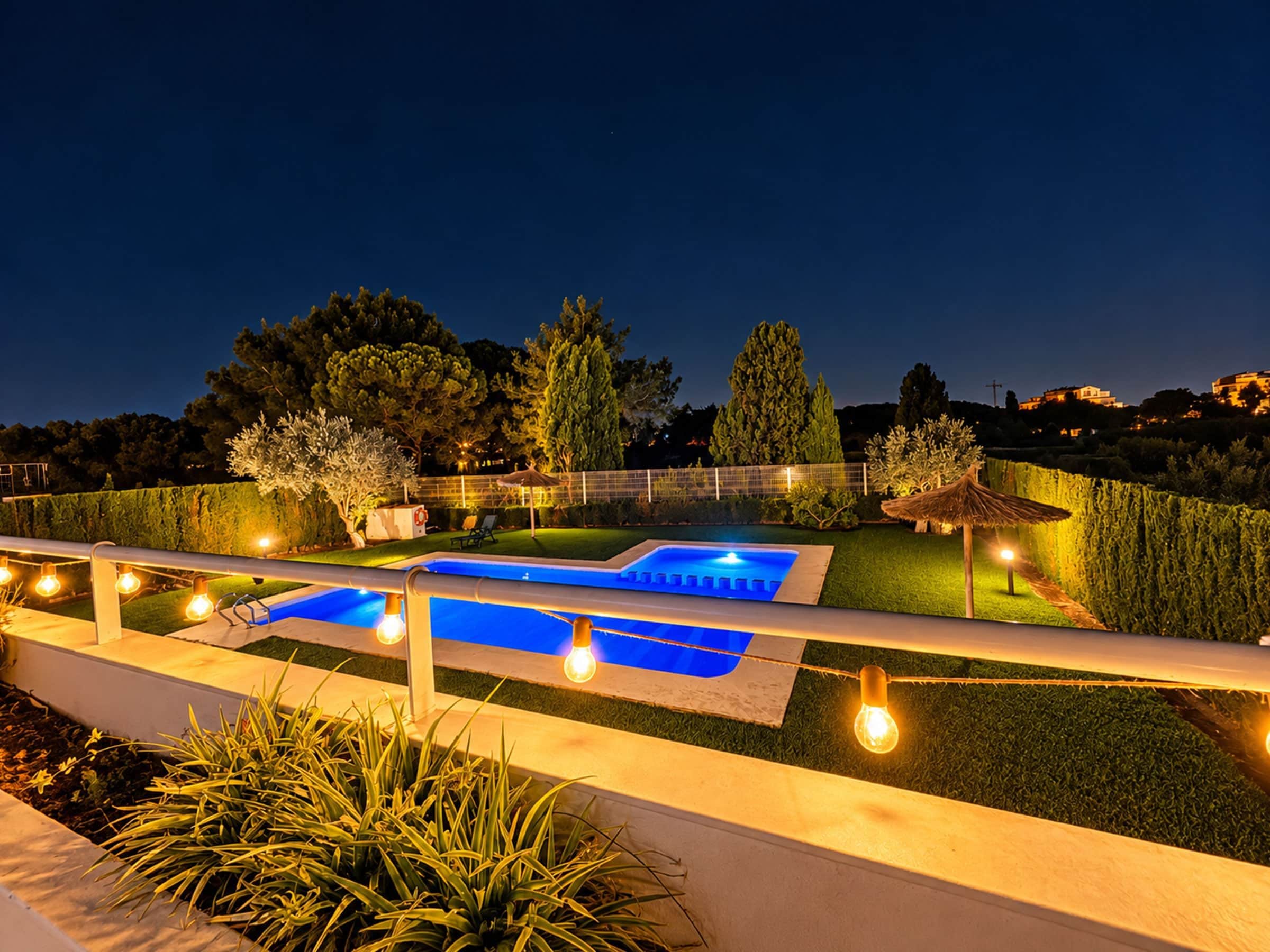 A swimming pool with a blue water feature, surrounded by a well-maintained lawn and hedges.