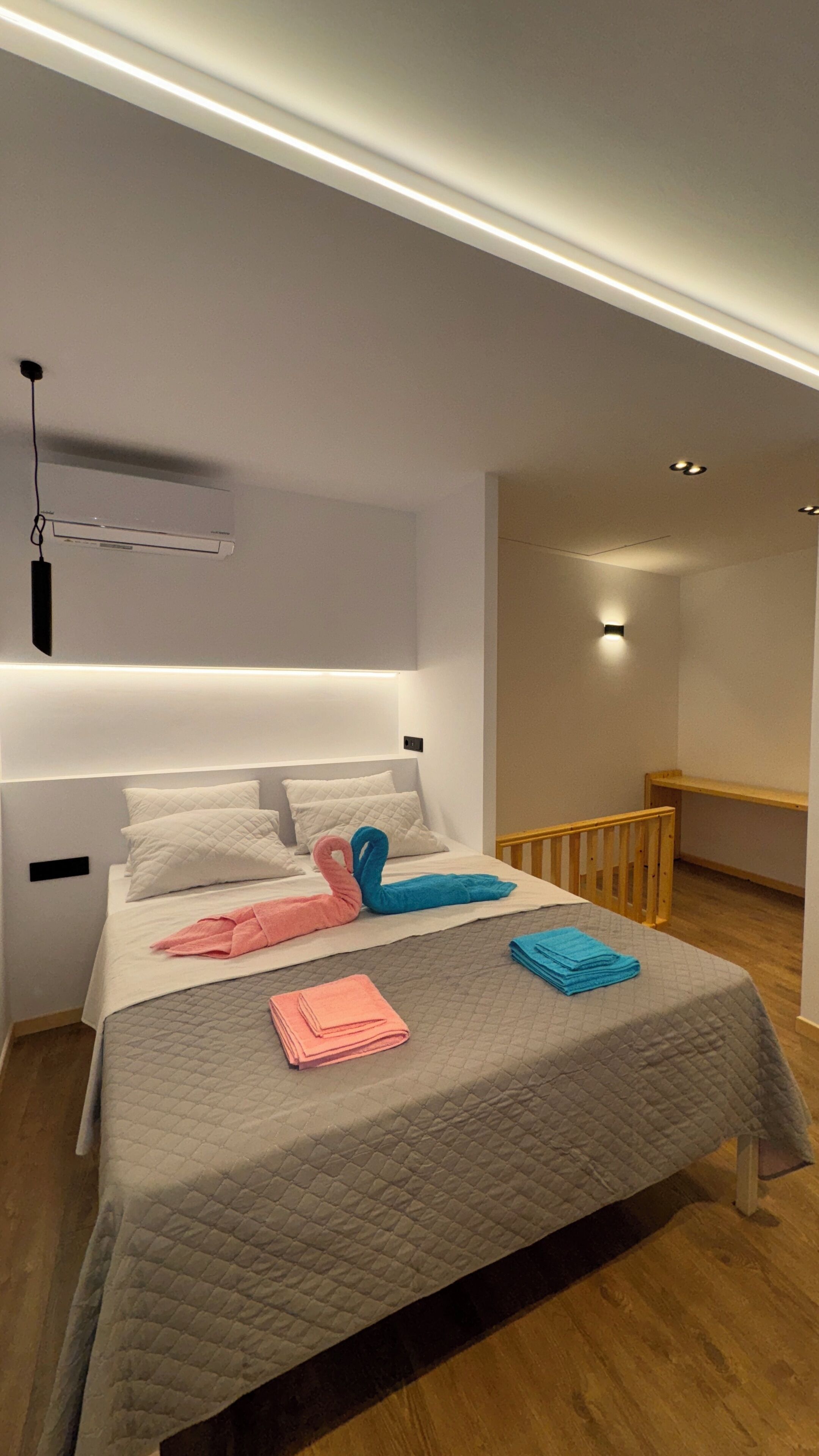 A modern bedroom with a bed, bedside tables, a hanging light fixture, and a built-in bench.