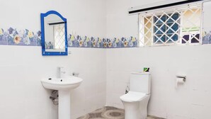 A bathroom with a white sink, a toilet, and a window with a white grid.