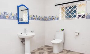 A bathroom with a white sink, a toilet, and a window with a white grid. - Large Modern 5BR 24/7 Power Diamond Hills(MAYLITE HOME)
 (Kumasi)