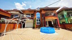 A two-story house with a swimming pool, a covered patio, and a large window.