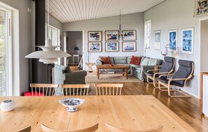A spacious living room with a wooden dining table, a sofa, and a lounge chair. - Amazing home in Kristinehamn with lake view (Kristinehamn)