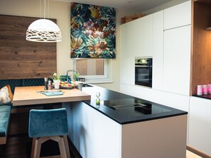 Una cocina moderna con una isla central, un comedor con banco y una pared de madera.
