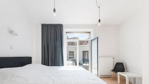 Quarto moderno com cama grande, vista para o exterior e varanda.