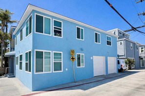 A two-story residential building with a blue exterior, a driveway, and a street sign indicating a one-way street. - New & Modern with Parking Steps to Bay & Boardwalk (San Diego)
