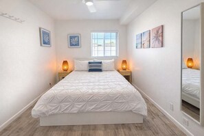 Un dormitorio con una cama grande, dos lámparas de noche, una ventana y decoración en la pared.