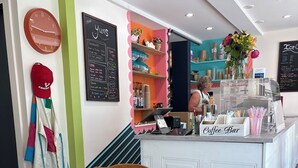 Ein Coffeeshop-Bereich mit einer Theke, einer Uhr und einer Speisekarte.