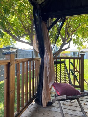 Une terrasse en bois avec un banc et un objet suspendu.