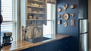 A kitchen with dark blue cabinets, a stainless steel refrigerator, and decorative wall plates. - Shackford House in Eastport (Eastport)