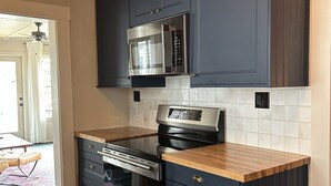 A kitchen with dark cabinets, a microwave, an oven, and a built-in dishwasher. - Shackford House in Eastport (Eastport)