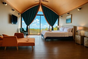 Ein Schlafzimmer mit einem Bett, einem Sessel, einem Nachttisch und Blick ins Freie.