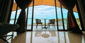 Ein Zimmer mit Meerblick, zwei Sessel, ein Tisch und ein Sofa.