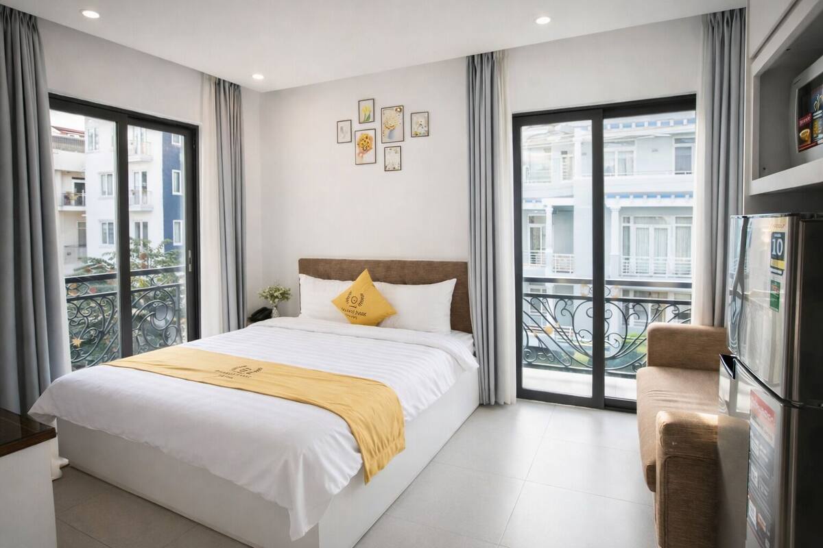 Et moderne hotelværelse med en stor seng, en sofa, en balkon med udsigt og et køleskab.