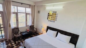 Ein Hotelzimmer mit einem Bett, einem Schreibtisch, einem Stuhl, einem Deckenventilator und einer Wandleuchte.