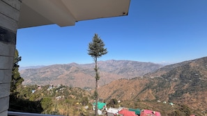 Vista de la montaña con un solo árbol y casas en el valle.