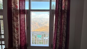 Ein Zimmer mit Fenster, Vorhängen und Bergblick.