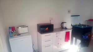 Una kitchenette compacta con refrigerador, microondas, tostadora y cafetera.