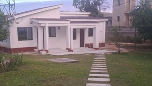 Una casa moderna de dos pisos con un porche cubierto, un camino de entrada pavimentado y un patio con césped.