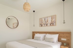 A bedroom with a wooden headboard, a round mirror, a painting, and a bedside table with a cup. - Aitherion – Villa with Pool & Upper Suite, Plakias (Τοπική Κοινότητα Ασωμάτου)