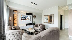 Uma sala de estar moderna com um sofá seccional, uma TV de tela plana e uma mesa de centro.