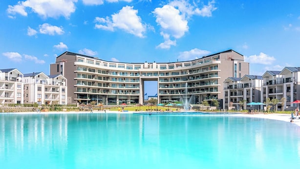 Um hotel com uma piscina grande, várias varandas e um pátio central.