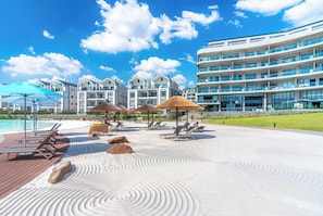 A resort with a pool, sun loungers, umbrellas, and a large building with balconies. - Waterfall penthouse (Midrand)