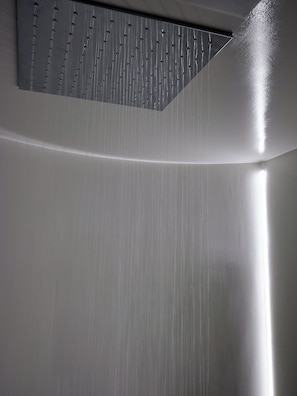 A modern shower with a vertical water flow design and a sloped ceiling. - Élure Tokyo (Tokyo)