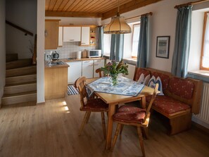Une cuisine chaleureuse avec des meubles en bois, une table à manger entourée de chaises et un banc.