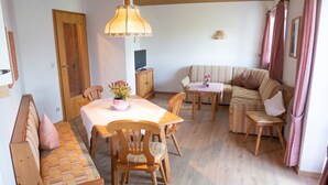 Una habitación acogedora con una mesa de madera, sillas, un sofá y un banco.