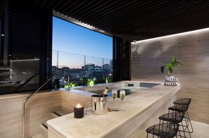 Eine moderne Bar mit Stadtblick, einem Whirlpool und einer Kerze.