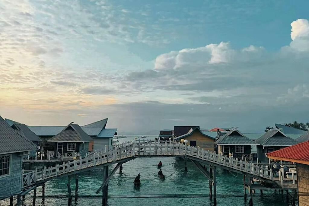 Overwater bungalows connected by a bridge over a lagoon.