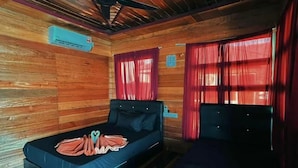 A cabin with a bed, a small table, and a window with curtains. - SEA WIN HOLIDAY (Mabul Island)