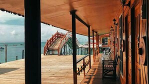 A wooden deck with a staircase leading to a dock, wooden walls, and a railing. - SEA WIN HOLIDAY (Mabul Island)