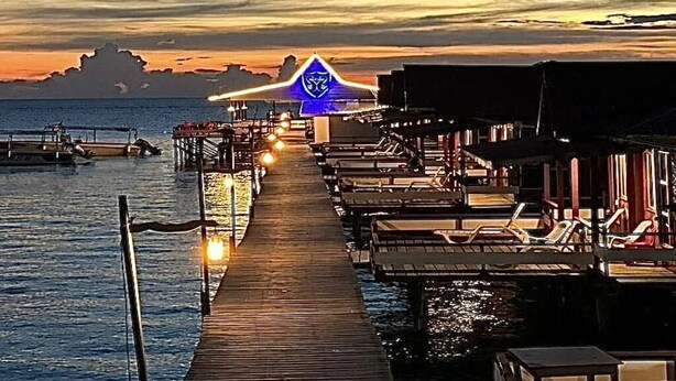 A pier leading to overwater bungalows with a sunset in the background. - SEA WIN HOLIDAY (Mabul Island)