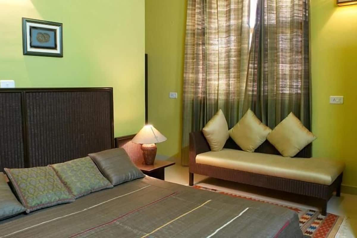 A room with a bed, a sofa, a lamp, and a curtain.