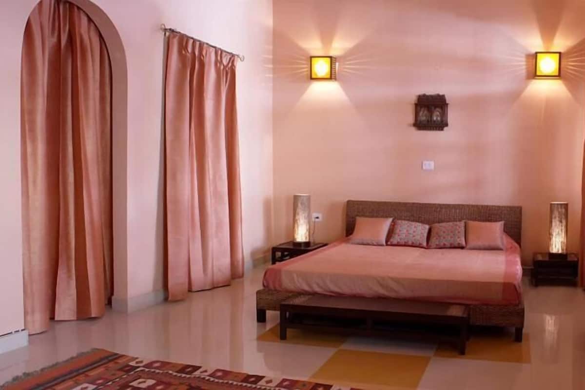 A bedroom with a bed, two wall sconces, a nightstand, and a rug.