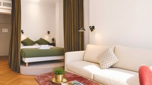 A modern hotel room with a bed, a sofa, a coffee table with a plant, and wall-mounted lights. - 345-Tronchet 1G - Stunning Apartment in Paris 8 (Paris)