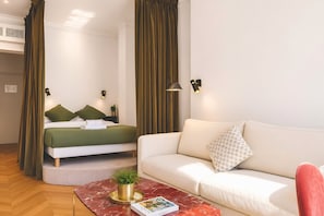 A modern hotel room with a bed, a sofa, a coffee table with a plant, and wall-mounted lights. - 345-Tronchet 1G - Stunning Apartment in Paris 8 (Paris)