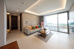 A modern living room with a sofa, coffee table, and a large window. - Haeundae Beach Restmons (Busan)