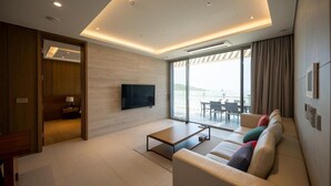 A modern living room with a sofa, a coffee table, a TV, and a large window with a view. - Haeundae Beach Restmons (Busan)