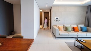 A modern living room with a sofa, a dining table, and a kitchen area in the background. - Haeundae Beach Restmons (Busan)