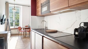 Ett modernt kök med en väggbeklädnad av marmor, träskåp, en diskho i rostfritt stål och en svart bänkskiva.